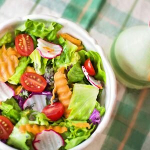 Colorful fresh vegetable salad with cherry tomatoes in a white bowl.