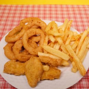 High angle of fried potato with onion rings and nuggets on plate on table near yellow wall
